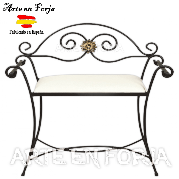 Banco descalzador de forja modelo Vélez-Blanco en hierro negro con detalle floral dorado y cojín blanco mullido en un dormitorio.